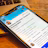 A smartphone displaying a social media profile is placed on a wooden table next to a laptop. The profile includes a picture, name, and details about a creator and photographer. The blue and white interface is visible on the phone screen.
